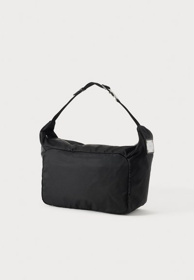 Sac d’épaule rectangulaire noir avec sangle ajustable et boucle argentée, présenté sur un fond uni clair.