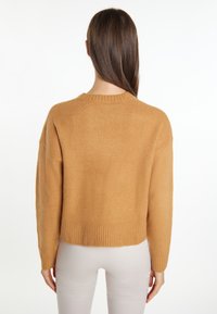 Pulover scurt, maro, dintr-un tricot moale și texturat, cu tiv și mansete ribbate. Decolteu rotund și design cu umeri căzuti.