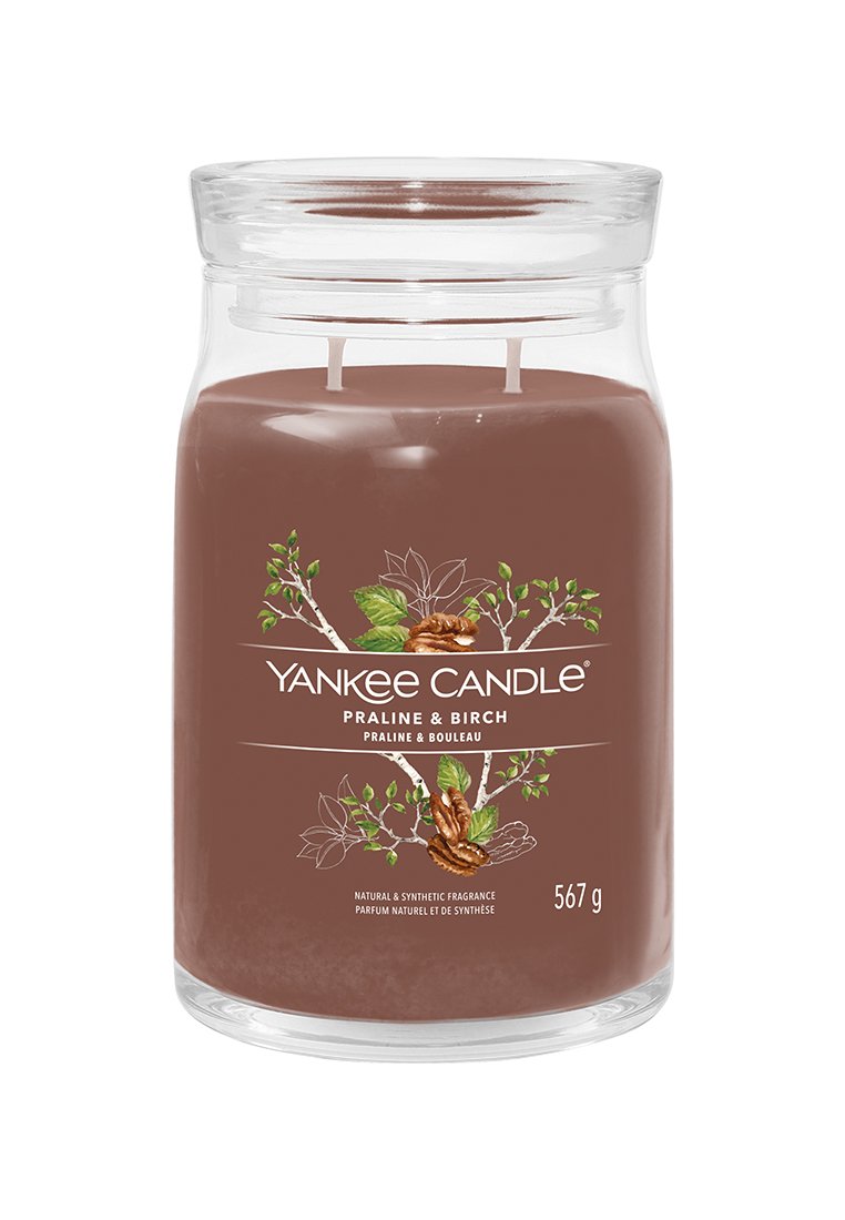 Bougie parfumée marron dans un pot en verre transparent avec une étiquette métallique, comportant deux mèches et des images décoratives de feuilles et de noix. 567 g.