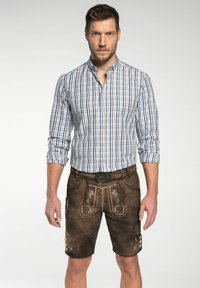 Karierter Button-Down-Hemd in Blau und Weiß, kombiniert mit braunem Lederhosen, versehen mit dekorativer Bestickung und Knöpfen an den Seiten.