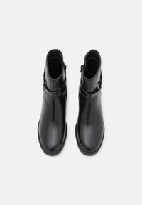 Botas de cuero negras hasta el tobillo con un acabado suave, que cuentan con un cierre de cremallera lateral y una hebilla decorativa en el tobillo.