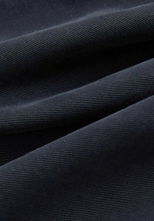 Dunkelmarineblauem Stoff mit feiner diagonaler Rippung, sanft gefaltet, um die Textur und die Webdetails hervorzuheben.