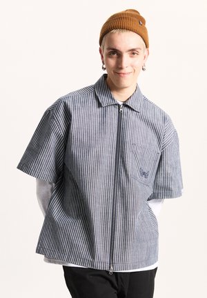 Striped short-sleeve shirt in navy and white with a zip front and collar. Features a chest pocket with an embroidered logo. Cotton blend material.