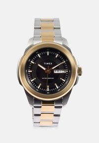 Zegarek Timex z czarną tarczą, złotą obręczą, metalowym paskiem w srebrnym i złotym kolorze oraz wyświetlaczem daty; podkreślona funkcja wodoszczelności.