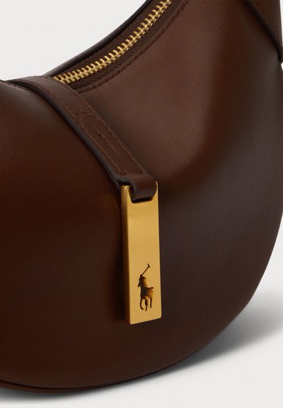 Καφέ δερμάτινη τσάντα χειρός με λεία υφή, που διαθέτει ένα χρυσό φερμουάρ και �ένα ορθογώνιο χρυσό διακοσμητικό με λεπτομέρεια λογότυπου.