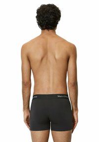 Boxer neri realizzati in un materiale morbido e elastico. Presentano un cinturino con logo e un design aderente, visti da dietro.
