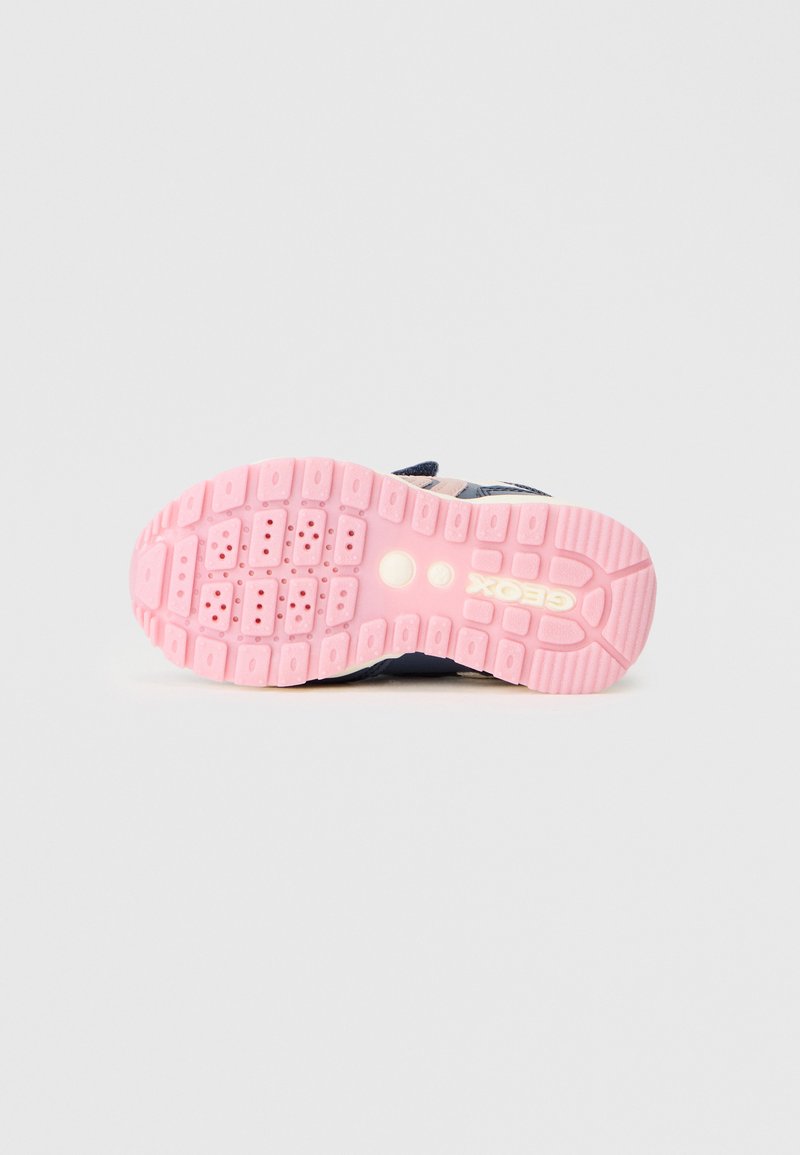 La semelle de la chaussure présente un design texturé avec du caoutchouc rose, des motifs hexagonaux et un logo. Conçue pour une meilleure adhérence et stabilité.