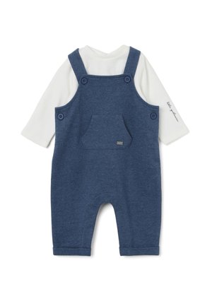 Pantalones de mezclilla azul con una camisa de manga larga blanca debajo. Presenta tirantes ajustables, dos botones grandes y un bolsillo frontal.