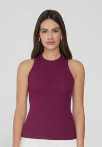 Top de tirantes ajustado de canalé en ciruela profundo con un cuello alto, diseño sin mangas y textura suave. Sin patrones ni acentos visibles.