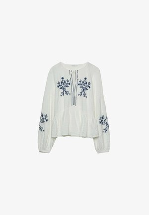 Vit broderad blus med långa ärmar, prydd med marinblå blommönster och en plisserad midja. Knytkragen ger en extra detalj till designen.