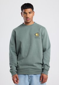 Green sweatshirt made of cotton blend, featuring a crew neck, long sleeves, and a yellow graphic logo on the chest.