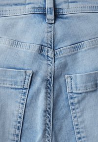 Pantalones de mezclilla azul claro con bolsillos traseros y costuras cosidas, que muestran una textura desgastada y un detalle trasero distintivo.