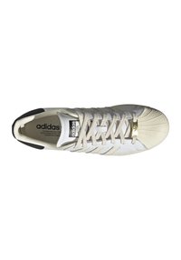 Adidas sporta apavi ar baltu ādas virsu, teksturētu krēmkrāsas purna daļu, beidzēm krāsas šņorēm un trim toņu svītrām. Melna akcenta detaļa pie papēža.
