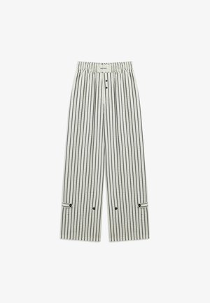 Szerokie spodnie wykonane z jasnej beżowej tkaniny w ciemne pionowe paski. Posiadają elastyczny pasek w talii, guziki z przodu oraz detale w formie mankietów.