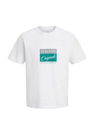 Adolescente con capelli ricci che indossa una t-shirt bianca con grafica, jeans blu a taglio largo e scarpe marroni, in piedi su sfondo bianco.