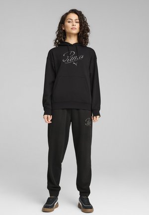Zwarte hoodie met een voorzak en logo, gecombineerd met bijpassende zwarte joggers met logodetail. Beide zijn gemaakt van zachte, comfortabele stof.
