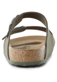 Green sandal with two adjustable straps, cork footbed, textured rubber sole, and smooth finish on upper for comfort and stability.