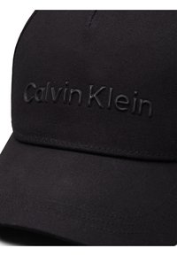 Must have musta kangas, millel on kumerä serv ja struktuurne kuju, esiküljel on reljeefne 'Calvin Klein' logo. Sile tekstuur.