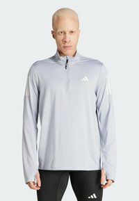 Lichtgrijs sportief langshirt met lange mouwen en een kwart-rits, voorzien van witte drie-streep branding op beide mouwen en een soepel, rekbaar materiaal.