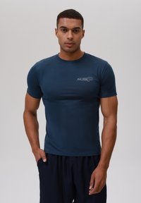 Camiseta de manga corta en azul marino de tela suave, con un corte ajustado y un pequeño logo que dice "Est. 1958" en la parte izquierda del pecho.