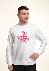 Felpa bianca con una grafica rosa che raffigura tre personaggi dei cartoni animati e un design a forma di cuore sul davanti. Tessuto morbido con polsini a coste.