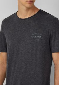 Szary t-shirt z okrągłym dekoltem, wykonany z miękkiej tkaniny. Posiada małe, nadrukowane logo na klatce piersiowej. Krótkie rękawy i standardowy krój.