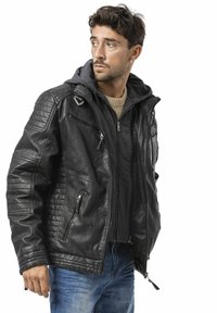 Zwarte leren jas met doorgestikte schouderaccenten, meerdere zakken met rits, gedragen over een grijze hoodie, met een geribde kraag.