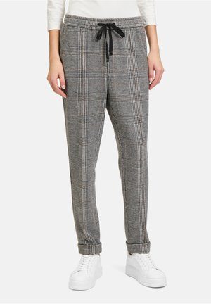 Grijze geruite joggerbroeken met een elastische tailleband, trekkoord en omgeslagen enkels, gecombineerd met witte sneakers.