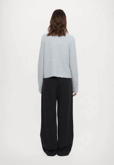 Lyseblå, fluffy genser med en kort design. Kombinert med løs passform svarte jeans, som har to baklommer. Enkel og teksturert.