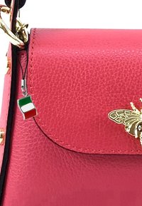 Rode leren handtas met een gouden bijaccent en een charm met de Italiaanse vlag. Gladde textuur en klep-sluiting.