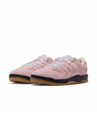 Des baskets en suede rose avec une semelle en caoutchouc noir et des lacets blancs, présentant un design texturé et des accents lisses le long de la tige.