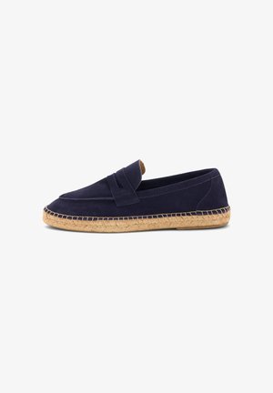 Mocassin en daim bleu marine avec semelle en jute tressée et détail de lanière sur le dessus, présenté sur un fond blanc.