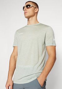 Lichtgroen T-shirt met korte mouwen met een subtiele textuur. Het heeft een klein wit logo op de borst en een aansluitend ontwerp.