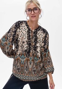Luźna bluzka z kwiatowym wzorem paisley w kolorach czarnym, kremowym i morskim. Posiada okrągły dekolt ze sznurkiem oraz długie, zwiewne rękawy.