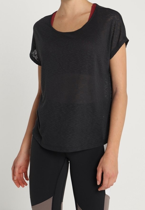Haut de sport noir à manches courtes, coupe ample, en tissu texturé avec un col large, superposé à un soutien-gorge de sport bordeaux.