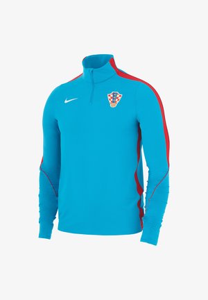 Jasnoniebieska sportowa bluzka z długim rękawem z czerwonymi paskami na rękawach, kołnierz z zamkiem do ćwiartki, logo Nike i herbem chorwackiej drużyny piłkarskiej na piersi.