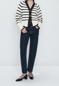 Sweter w paski w kolorze kremowym i granatowym, zapinany na guziki z prążkowanymi mankietami. Połączony z ciemnoniebieskimi jeansami prostymi i czarnymi, sznurowanymi balerinkami.