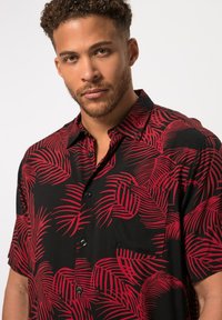 Korte mouwen overhemd in zwart met een rood palmbladpatroon, voorzien van een zak en een relaxte pasvorm. Textuurstof met een gladde oppervlakte.