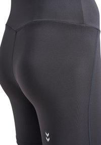 Svarta åtsittande leggings med en slät textur, sydda sömmar och en logotyp med tre vita chevroner på underbenet.