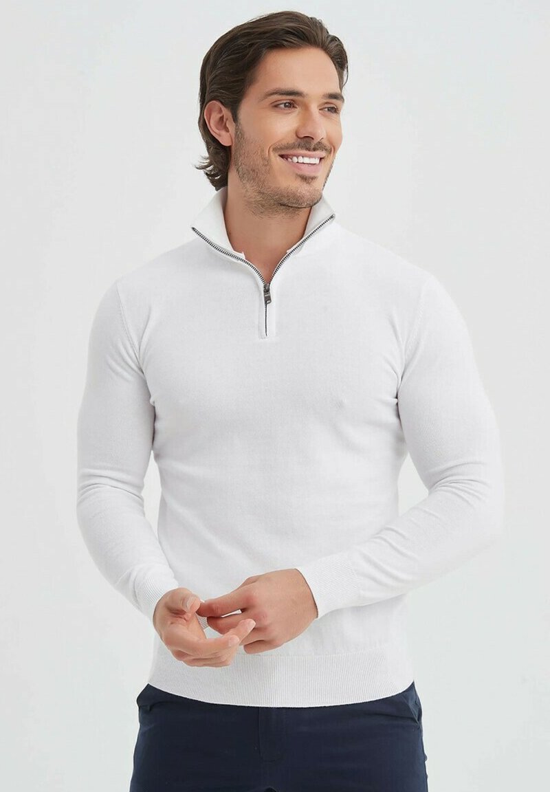 Pull blanc avec un design à mi-zip, fabriqué à partir d'un matériau tricot doux. Les longues manches et les poignets côtelés accentuent sa silhouette ajustée.