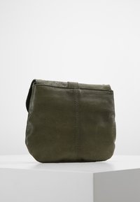 Borsa di pelle verde oliva con texture morbida, forma rettangolare, dettagli di cucitura discreti e una tracolla singola.