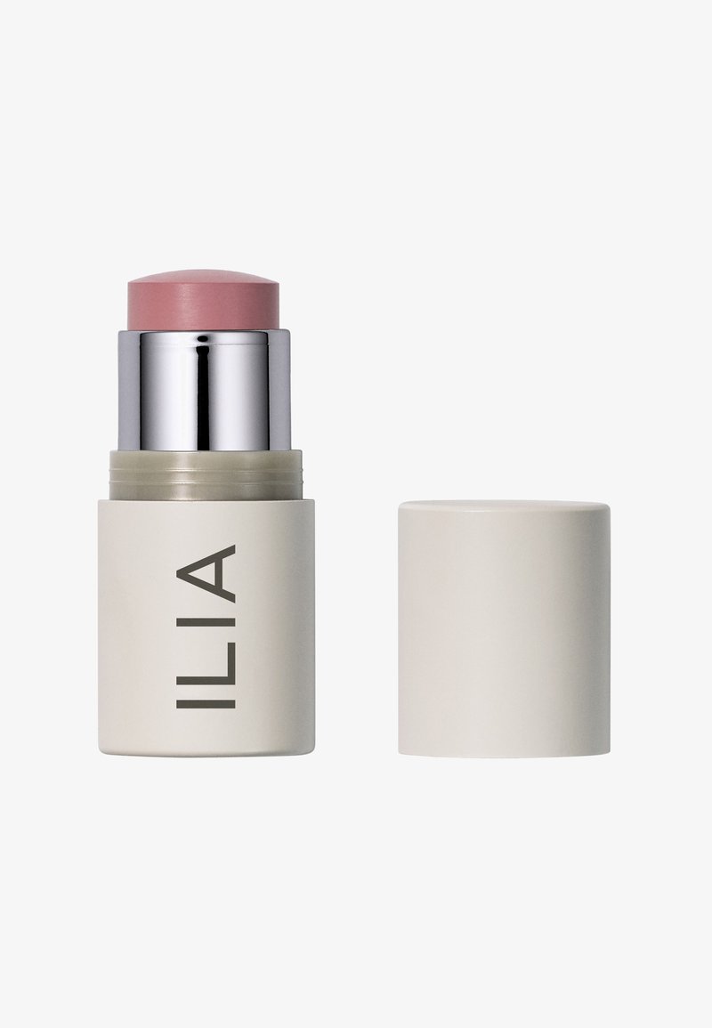Ilia crema blush stick in confezione beige chiaro, con una punta rotonda rosa. Texture liscia, cappuccio argento, design minimalista e branding chiaro.