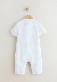 Détente en coton blanc avec des manches courtes, des poignets élastiques et de la dentelle sur les manches. Conçu avec une coupe décontractée et un col arrondi.