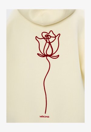 Haut à capuche crème avec un motif de rose rouge brodé au dos, doté d'une texture lisse et d'une capuche ajustable. Agrémenté d'une étiquette de marque.