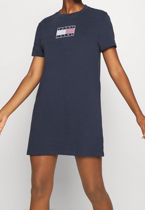 Robe t-shirt en coton bleu marine avec un col rond et des manches courtes ; présente un logo rectangulaire brodé en rouge, blanc et bleu sur la poitrine.