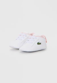 Des chaussures en toile blanches avec des accents et des lacets roses. Présentent le logo crocodile de Lacoste. Bout rond et semelle texturée pour une meilleure adhérence.