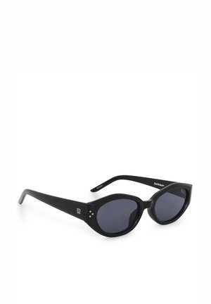 Zwarte ovale zonnebril met dikke monturen en donkere glazen, met een klein wit logo op het pootje en drie zilveren stippen bij het scharnier.