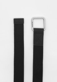 Curea din material textil neagră cu o cataramă metalică rectangulară de culoare argintie. Curea are o textură netedă și un accent contrastant din piele neagră aproape de cataramă.