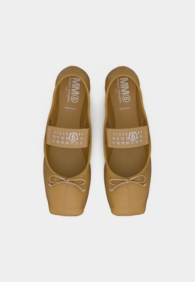 Ζευγάρι καφέ μπαλαρίνες με ελαστικούς σταυρωτούς ιμάντες που φέρουν λευκούς αριθμούς και το λογότυπο «6», στρογγυλεμένες τετράγωνες μύτες και μικρά φιόγκους στο μπροστινό μέρος.