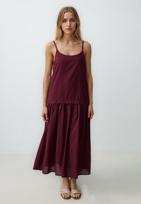 Abito maxi senza maniche bordeaux con corpetto aderente e gonna a strati fluida, realizzato in tessuto leggero. Design semplice con spalline regolabili.